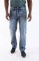 A person wearing light blue denim jeans with a faded wash, paired with a dark green shirt and dark navy shoes, shown from the waist down against a plain white studio background.