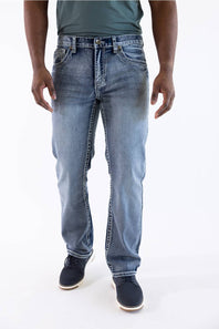 A person wearing light blue denim jeans with a faded wash, paired with a dark green shirt and dark navy shoes, shown from the waist down against a plain white studio background.