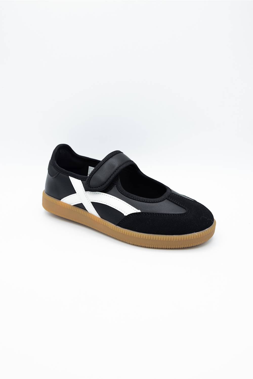 A black slip-on shoe with a white side stripe and a brown gum sole, photographed on a clean white background.