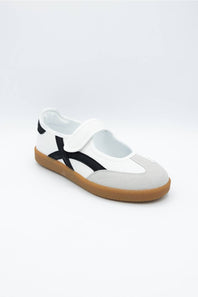 A white slip-on shoe with a black side stripe and a brown gum sole, photographed on a light gray background.