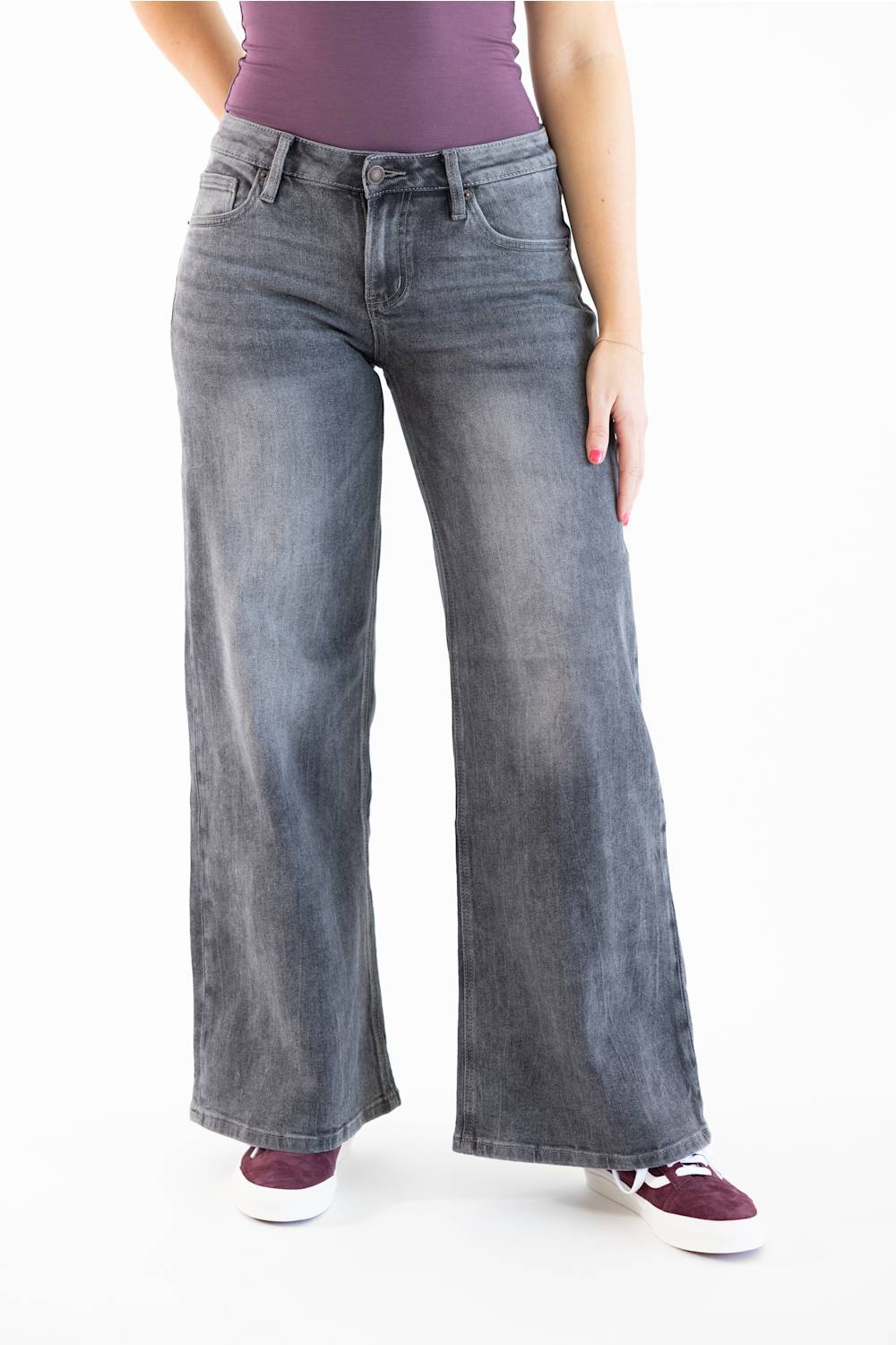 A person wearing wide-leg gray denim jeans with a faded wash, paired with a purple top and dark purple sneakers, shown against a plain white studio background.