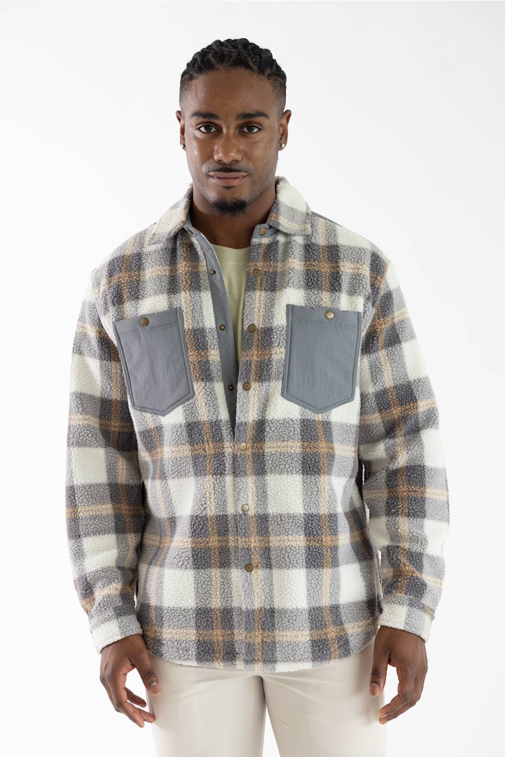 A man wearing a long-sleeve plaid flannel shirt with gray chest pockets, photographed against a plain white studio background.