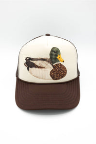 C.C. Mallard Duck Trucker Hat for Women in Cream and Brown. Front product view of the cap, featuring a white foam front panel with a detailed patch-stitch mallard duck graphic, brown mesh back, and brown adjustable snapback brim.