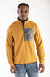 Front-facing studio shot of a model wearing the Marsh Wear Sullivan Quarter Zip Pullover in Buckthorn Brown, featuring a textured ribbed design, dark grey inner stand-up collar, front quarter-zip closure, and a zip chest pocket with a camouflage pattern accent, paired with light-wash blue jeans.