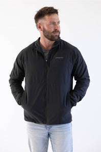 man standing in front of a white background looking off to the side in a patagonia jacket 