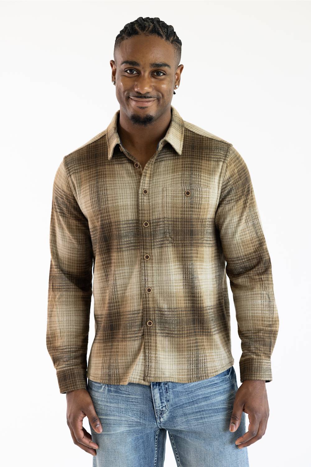 A man wearing a brown and beige plaid long-sleeve button-down shirt with blue jeans, standing against a plain white background.
