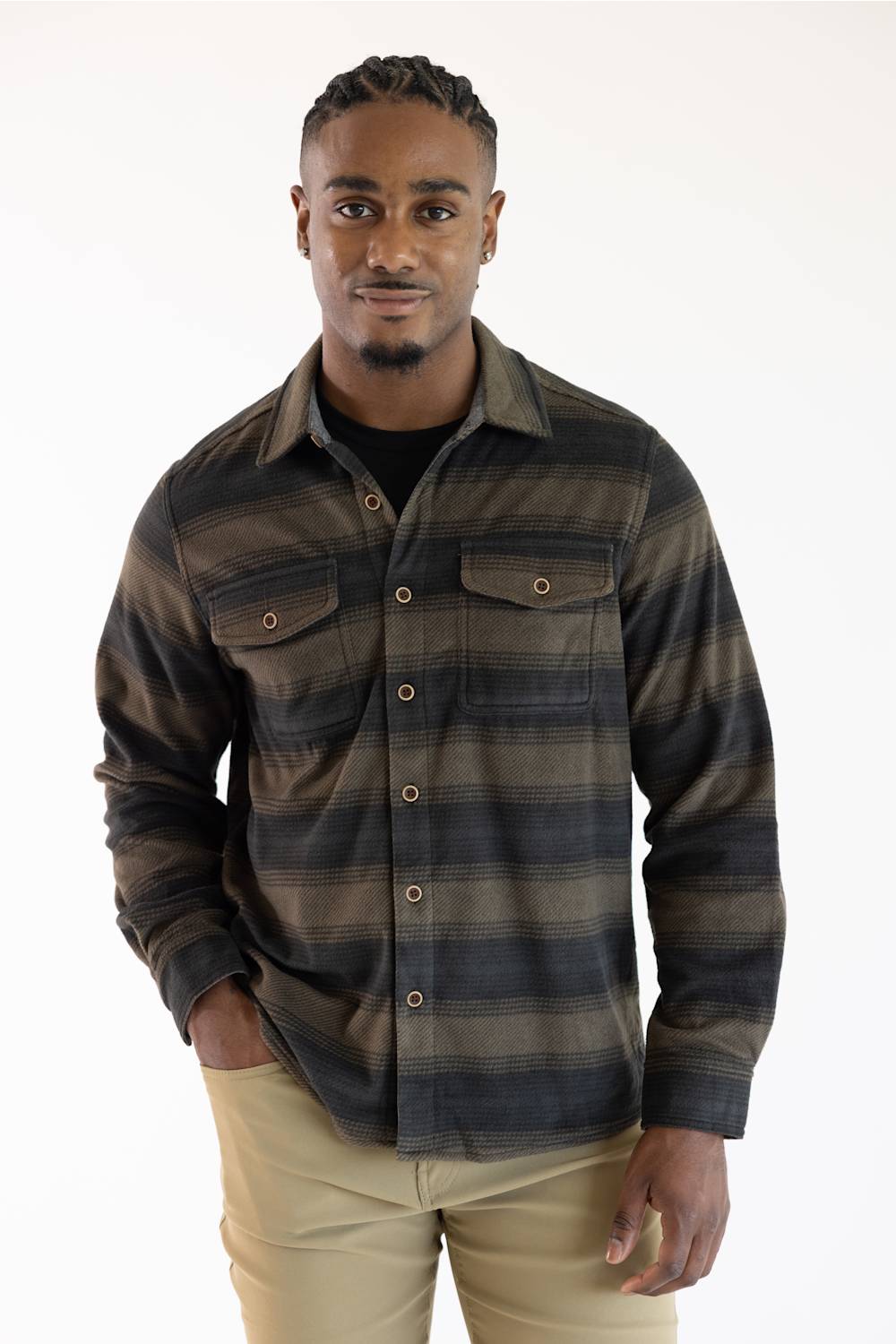 A man wearing a dark brown and black plaid button-down shirt with two chest pockets, paired with khaki pants, against a plain white background.