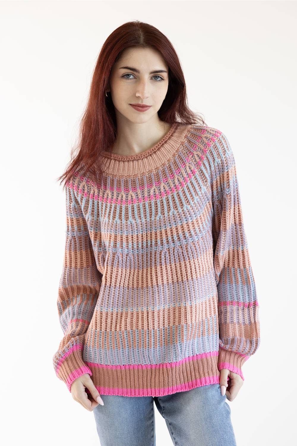 A woman with red hair wearing a long-sleeve knit sweater with horizontal stripes in beige, pink, and light blue, paired with light blue jeans, against a plain white background.