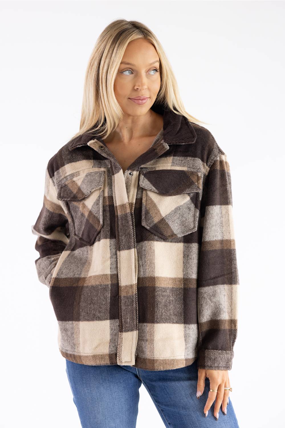 A woman wearing a brown, beige, and gray plaid button-up flannel shirt jacket with blue jeans, photographed against a plain white background.