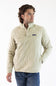A man wearing an off white Patagonia quilted pullover jacket with a stand collar and zippered chest pocket, paired with blue jeans, against a plain white studio background.