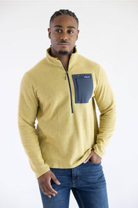 A man wearing a yellow textured quarter-zip fleece pullover with a dark gray chest pocket and blue jeans, photographed against a plain white studio background.