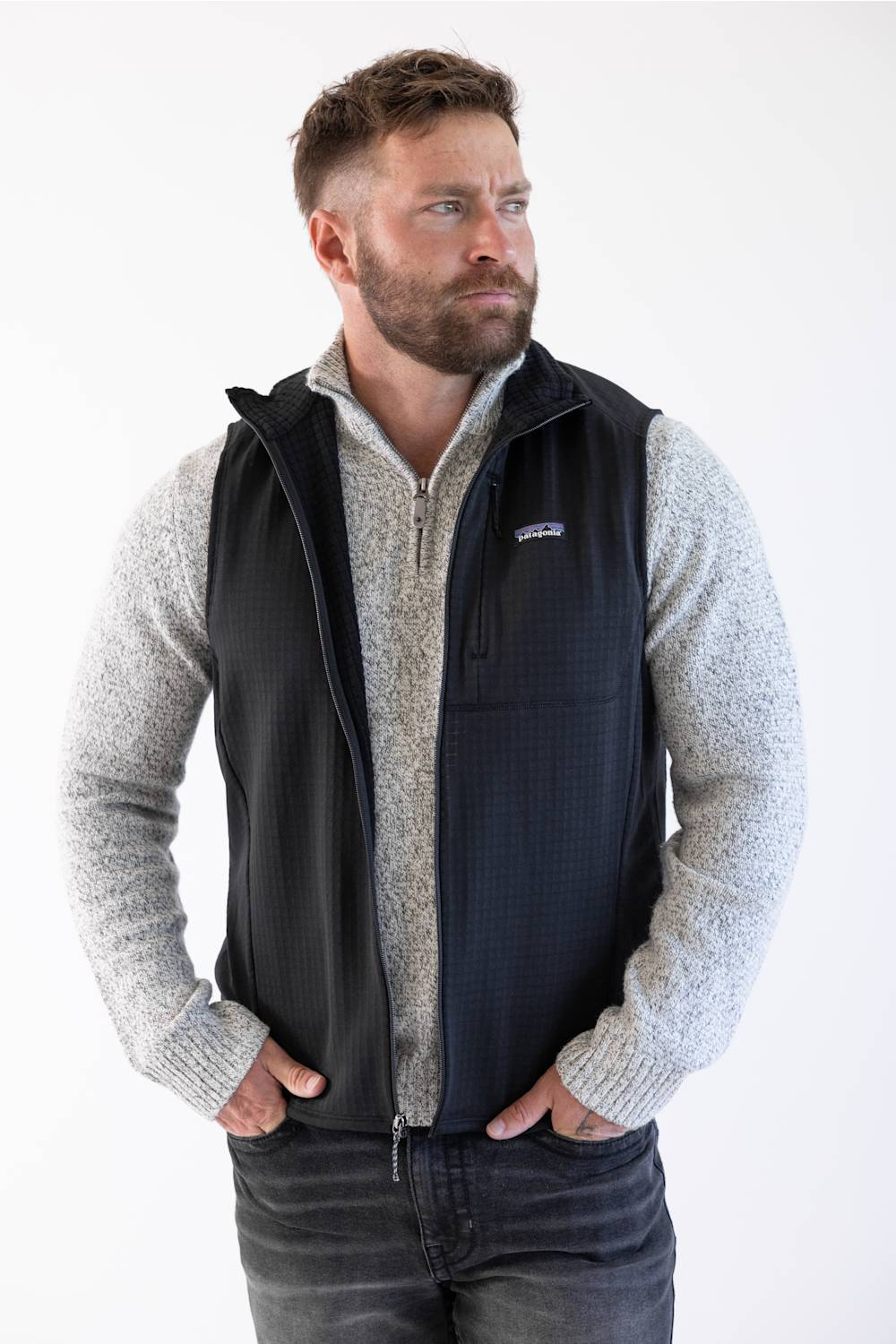 Patagonia Men's R1 Vest in Black styled over a heather grey quarter-zip sweater and dark jeans