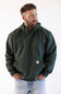 Model wearing a men's dark green forestry hoodie with hands in front pockets paired with light wash denim jeans.