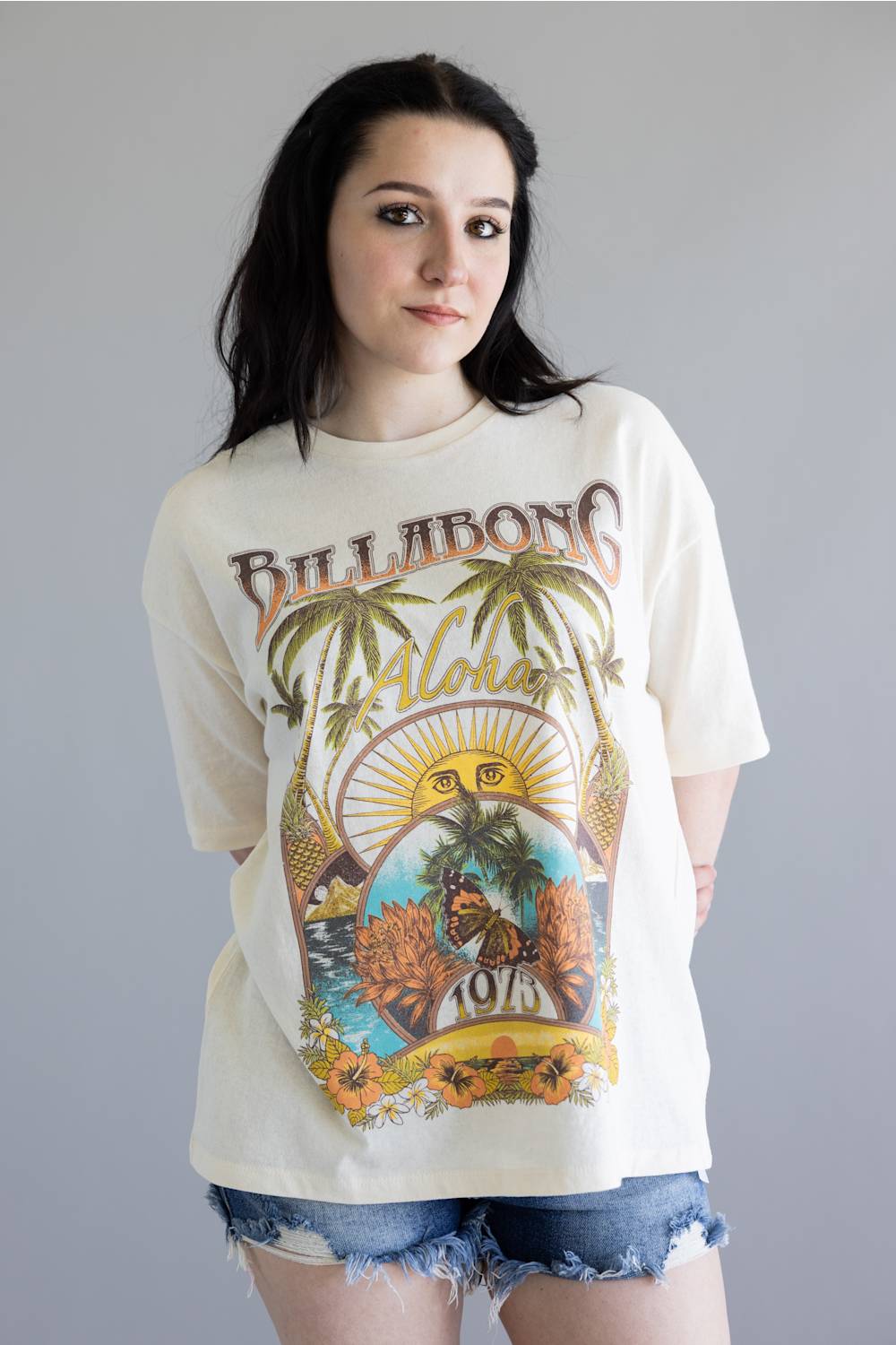 Woman wearing a Billabong t-shirt with a colorful graphic design on a gray background