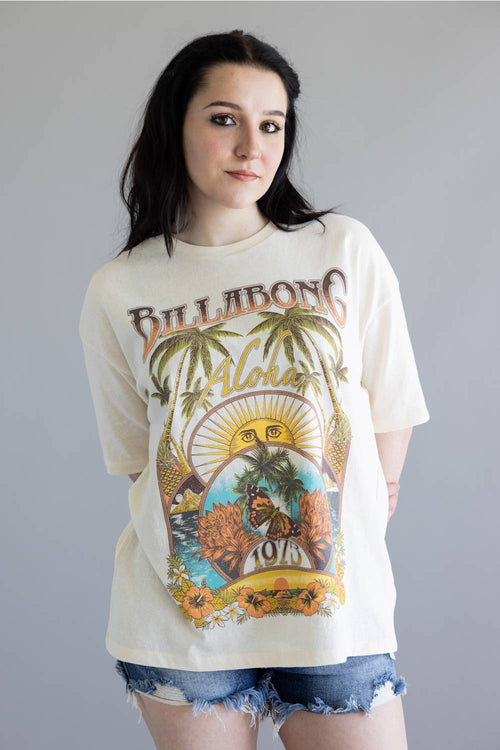 Woman wearing a Billabong t-shirt with a colorful graphic design on a gray background