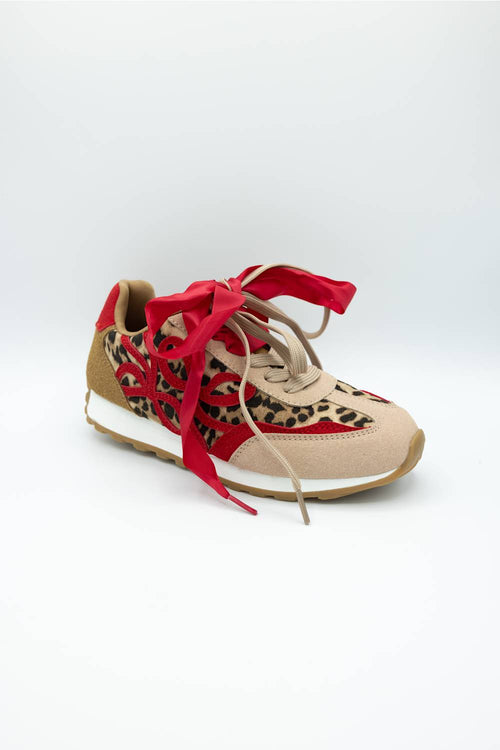 A low-top sneaker featuring a beige suede upper with a red and black leopard print overlay, red laces, and a white midsole with a gum outsole, shown on a light gray background.