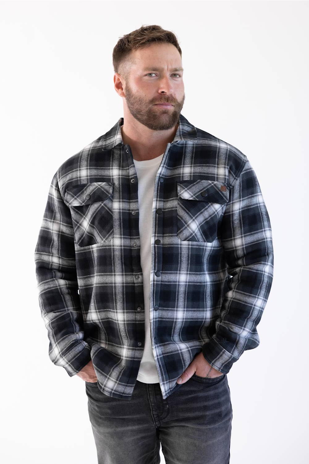 man with his hands in his front pockets, modling a sherpa lined flannel shacket 