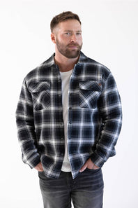 man with his hands in his front pockets, modling a sherpa lined flannel shacket 