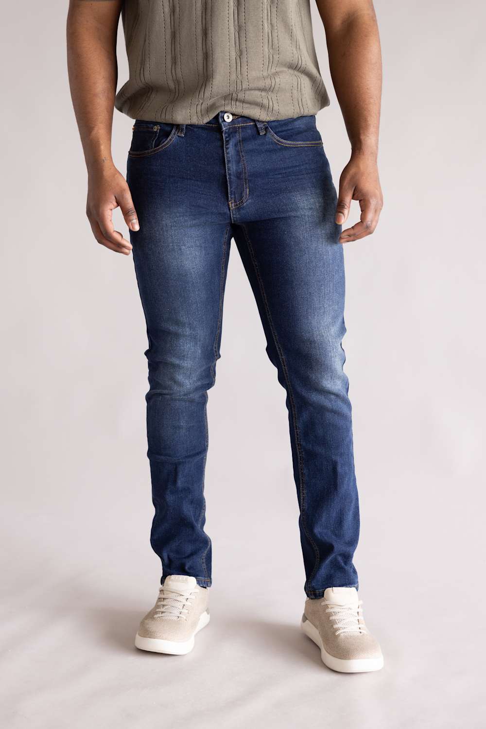 Front view of a person wearing blue jeans and a light-colored shirt on a plain background. The blue jeans are named Weatherproof Vintage Slim Jeans for Men in Silt Blue.
