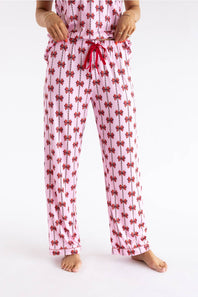 Pink pajama pants with a red bow and vertical stripe pattern, featuring a red drawstring waist, modeled on a person against a white studio background.