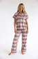 A woman modeling a matching short-sleeve button-up pajama top and wide-leg pajama pants set, both featuring an all-over repeating print of colorful cartoon soldiers on a white background, against a plain white studio backdrop.