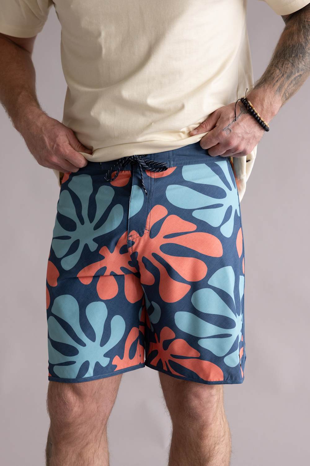 Front view of a person wearing blue shorts with orange and green abstract patterns on a plain background. The shorts are named Quiksilver Sol Tiles 19" Boardshorts for Men in Dark Denim.