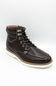A dark brown leather lace-up ankle boot with silver metal eyelets, a tan midsole, and a white outsole, shown on a light gray background.