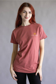 A short-sleeve crewneck t-shirt in a dusty rose or muted coral pink color, featuring a small yellow and white 'simple natural' logo on the left chest, displayed flat against a white background.