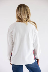 Back view of a blonde model wearing the Simply Southern Cream Cow Sweater with red plaid side trim details, paired with dark blue jeans.
