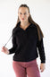 A woman modeling a black long-sleeve quarter-zip pullover sweatshirt with a mock neck, paired with dusty rose pants, against a plain white studio background.