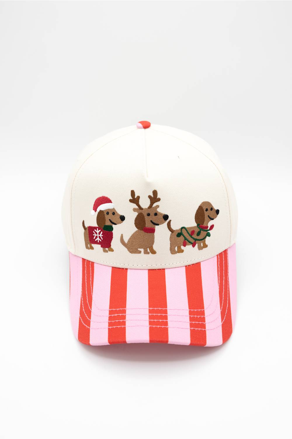 Front view of the Simply Southern Santa Dogs Holiday Hat in Cream/Stripe against a white background, featuring three embroidered dachshunds dressed in Christmas outfits on the cream front panel and a vertical red and pink striped visor.
