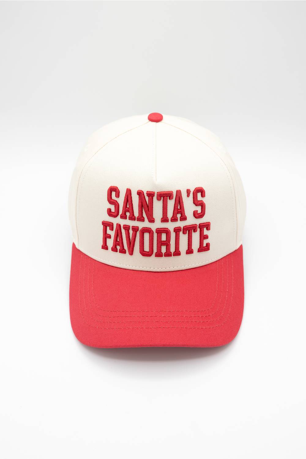 Front view of the Simply Southern Santa’s Favorite Holiday Hat in Cream/Red against a white background, featuring red embroidered collegiate-style lettering reading “SANTA’S FAVORITE” on the cream front panel and a solid red visor.