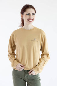 A woman wearing a tan long-sleeve crewneck shirt with a small embroidered 'simply southern' logo on the left chest, set against a plain white background.