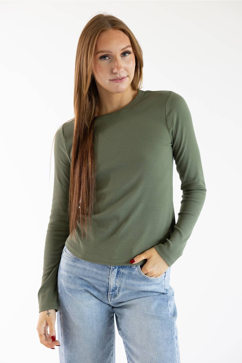 A woman modeling a long-sleeve crewneck top in olive green, paired with light-wash blue jeans, against a plain white studio background.