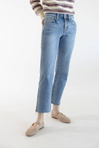 A person wearing light-wash blue cropped jeans with a striped knit top and beige loafers, standing against a plain white studio background.