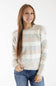 A woman with long light brown hair wearing a cream, beige, and light gray striped cable-knit sweater and blue jeans, standing against a plain white studio background.
