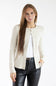 A woman modeling a cream ribbed knit cardigan over a white top and black faux-leather pants, photographed against a plain white studio background.
