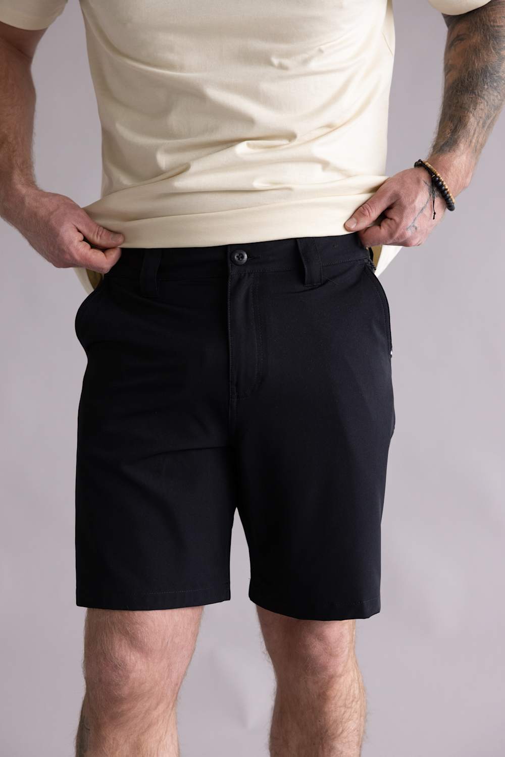 Person wearing black shorts and a beige shirt on a plain background. The shorts are the Quiksilver Taxer Amphibian 18" Hybrid Shorts for Men in Black