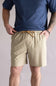 Person wearing a navy shirt and beige shorts on a plain background. The beige shorts are the Quiksilver Taxer Amphibian 18" Hybrid Shorts for Men in Twill 