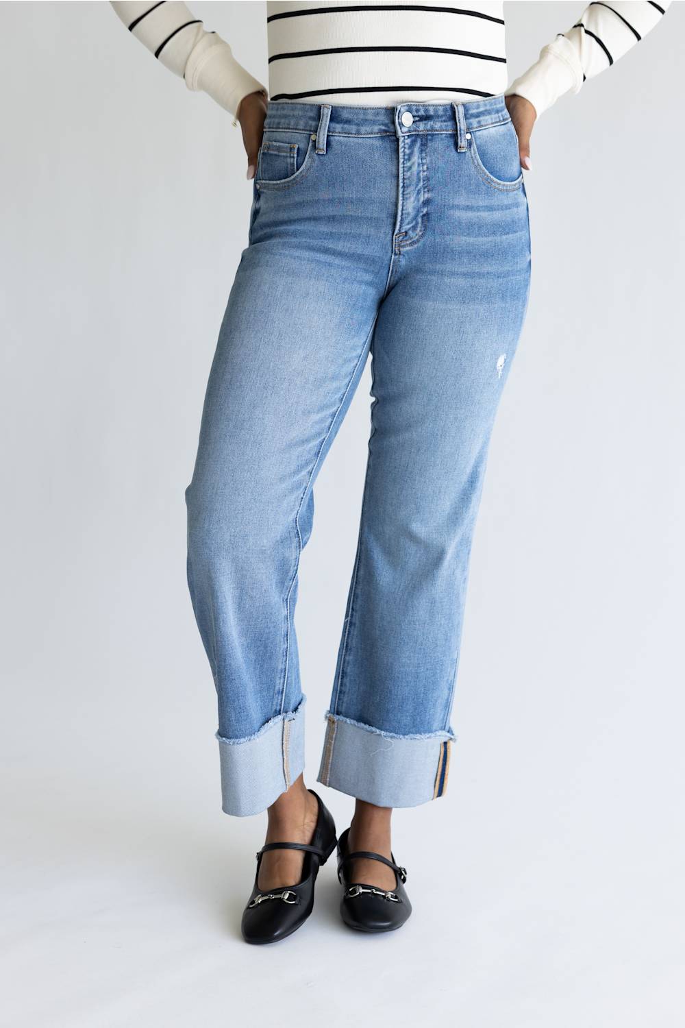 Woman wearing striped shirt with straight leg jeans and cuffed leg. 