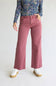 A model wearing dusty rose wide-leg jeans, a blue floral long-sleeve top, and white platform sneakers, standing against a light gray studio background.