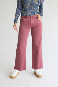 A model wearing dusty rose wide-leg jeans, a blue floral long-sleeve top, and white platform sneakers, standing against a light gray studio background.