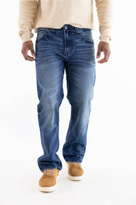 A person wearing medium-wash blue jeans, a cream long-sleeve shirt, and tan suede shoes, shown from the chest down against a plain white studio background.