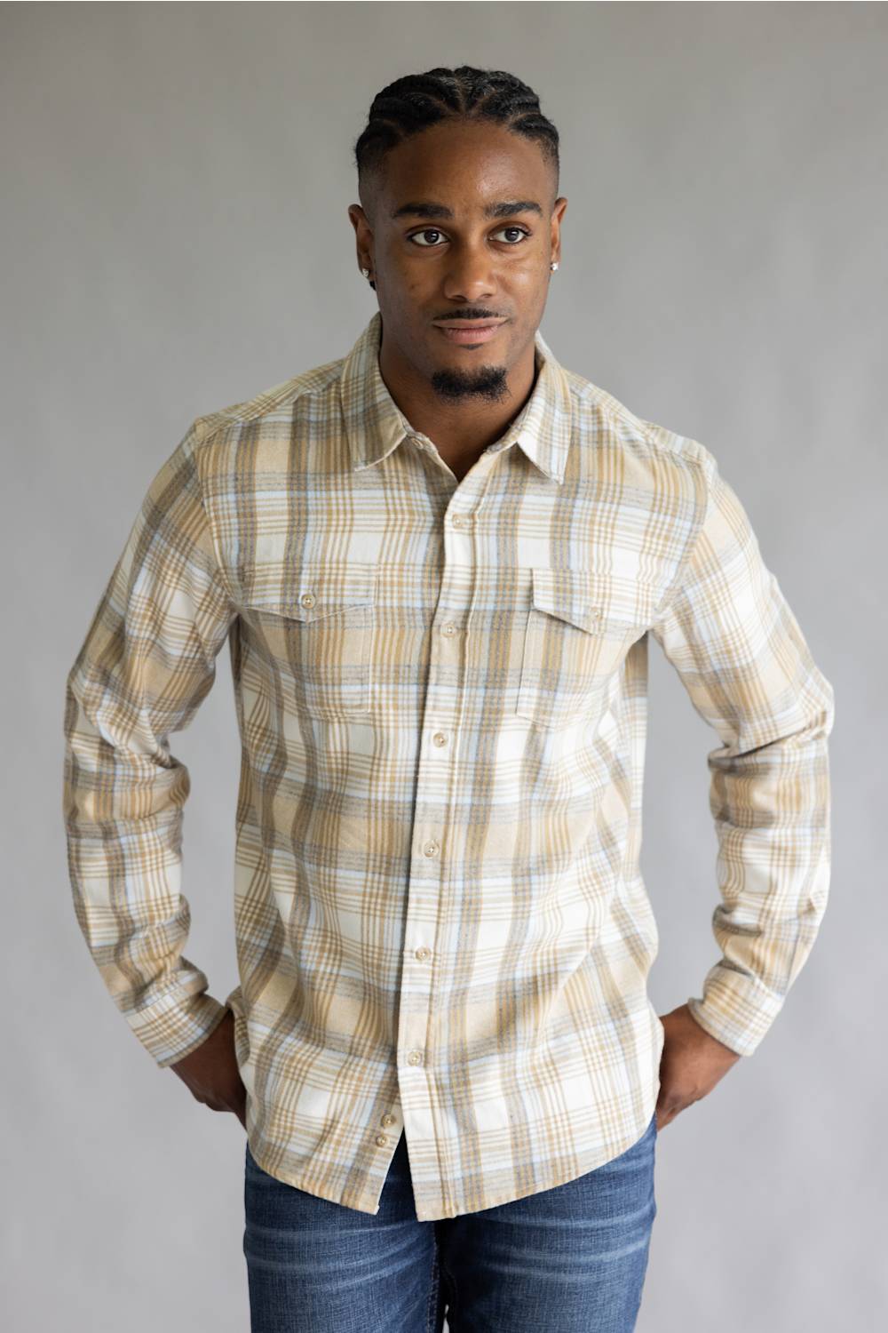 Front view of a model wearing the Split Men's long-sleeve flannel shirt in a beige, white, and light blue plaid pattern, featuring two button-flap chest pockets, styled with blue jeans against a grey studio background.
