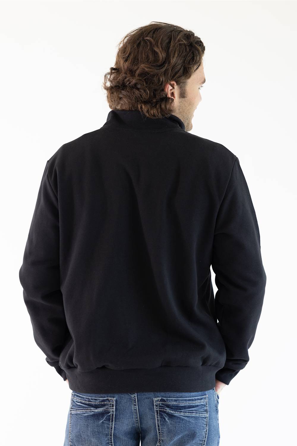 A man viewed from behind wearing a black long-sleeve quarter-zip pullover jacket and blue jeans, set against a plain white studio background.