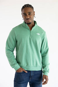 A man wearing the The North Face Evolution Simple Dome ¼ Zip Neck for Men in Dimmed Algae Green with a white The North Face Logo on the upper left chest.