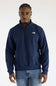 A man wearing a navy long-sleeve quarter-zip pullover jacket and blue jeans, set against a plain white studio background.