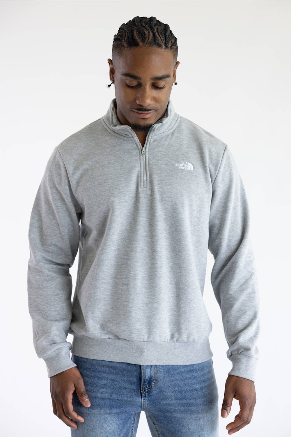 A man wearing a heather grey quarter zip The North Face men's sweatshirt with a white logo on the upper left chest.