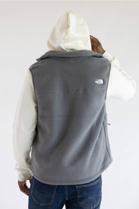 A person shown from the back wearing a gray fleece vest over a cream hoodie and blue jeans, with The North Face logo visible on the upper back.