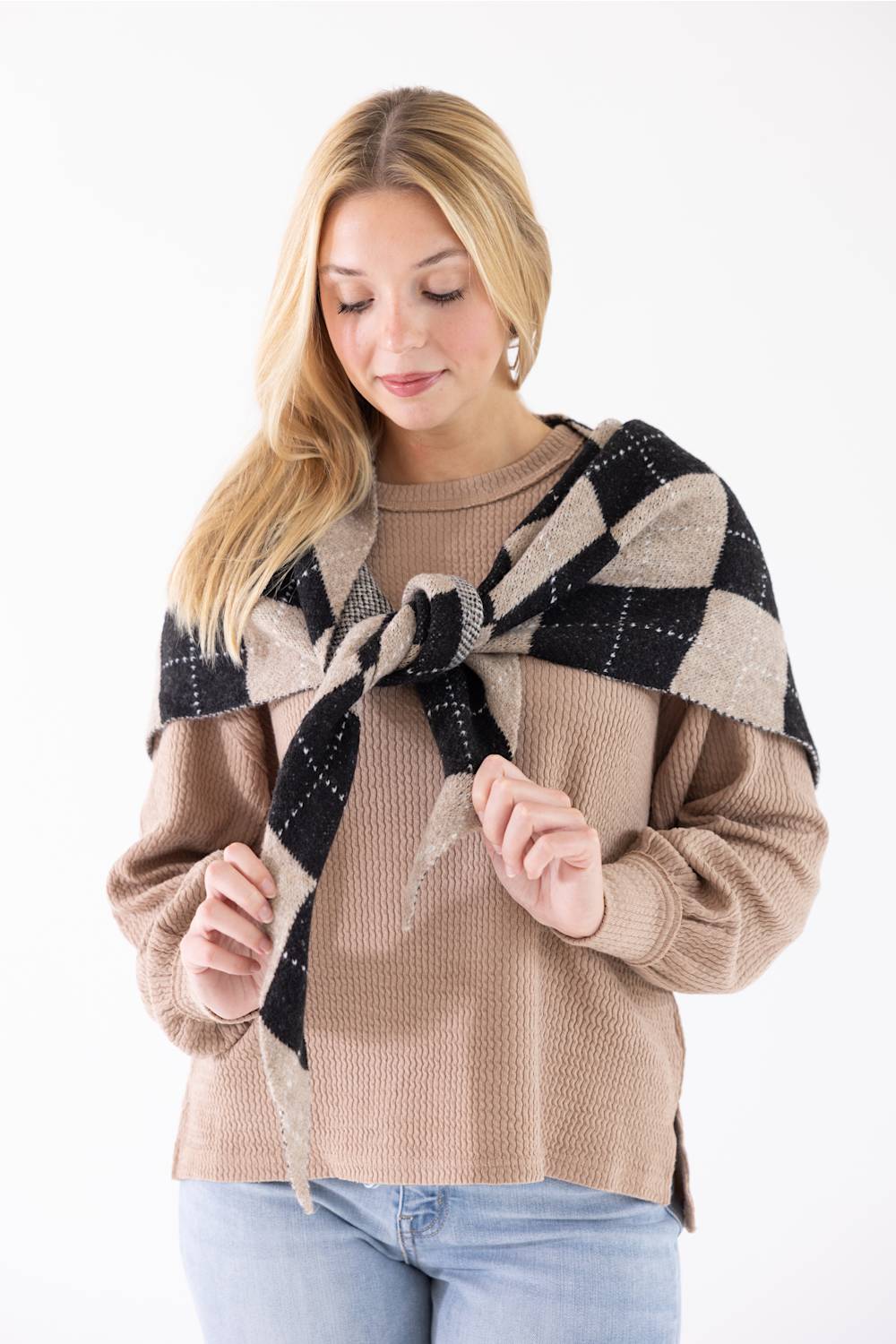 Woman wearing the Triangle Argyle Wool Scarf for Women in Taupe tied over her shoulders over a beige knit sweater.